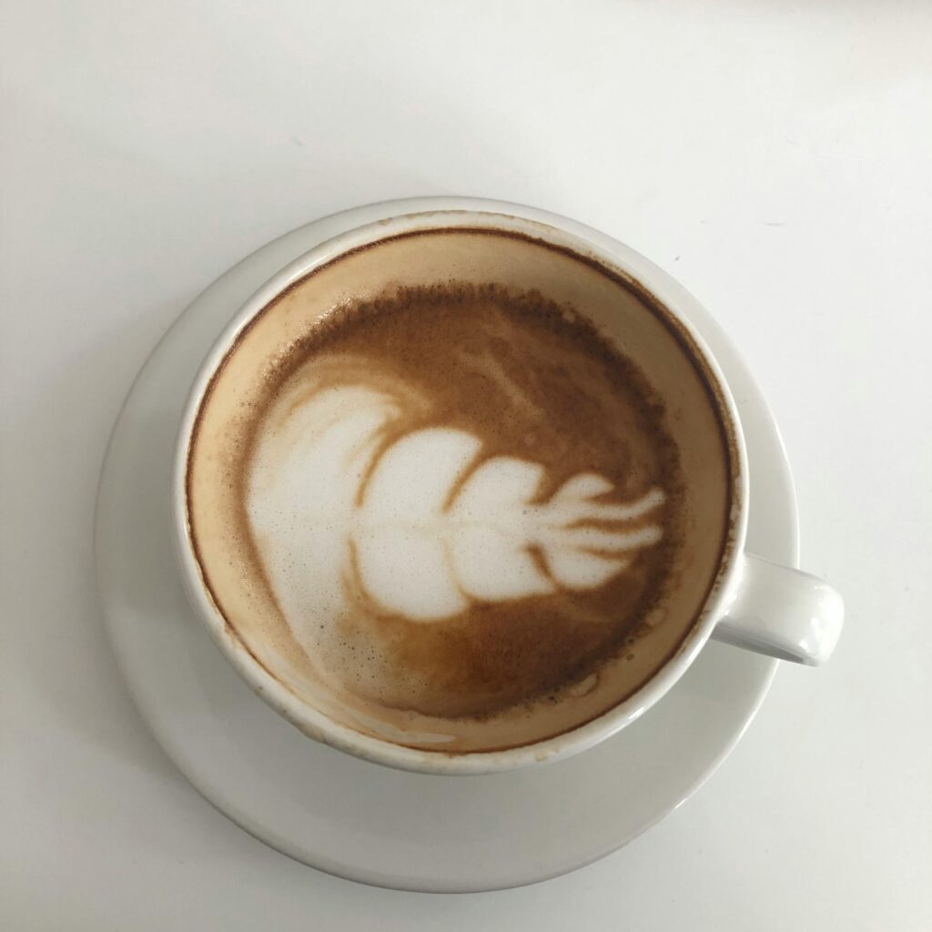 A top-down view of a coffee cup featuring intricate latte art on a white surface.